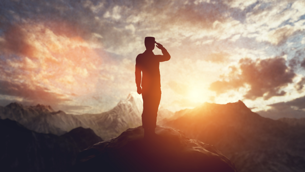 An individual standing on top of a mountain at sunset.